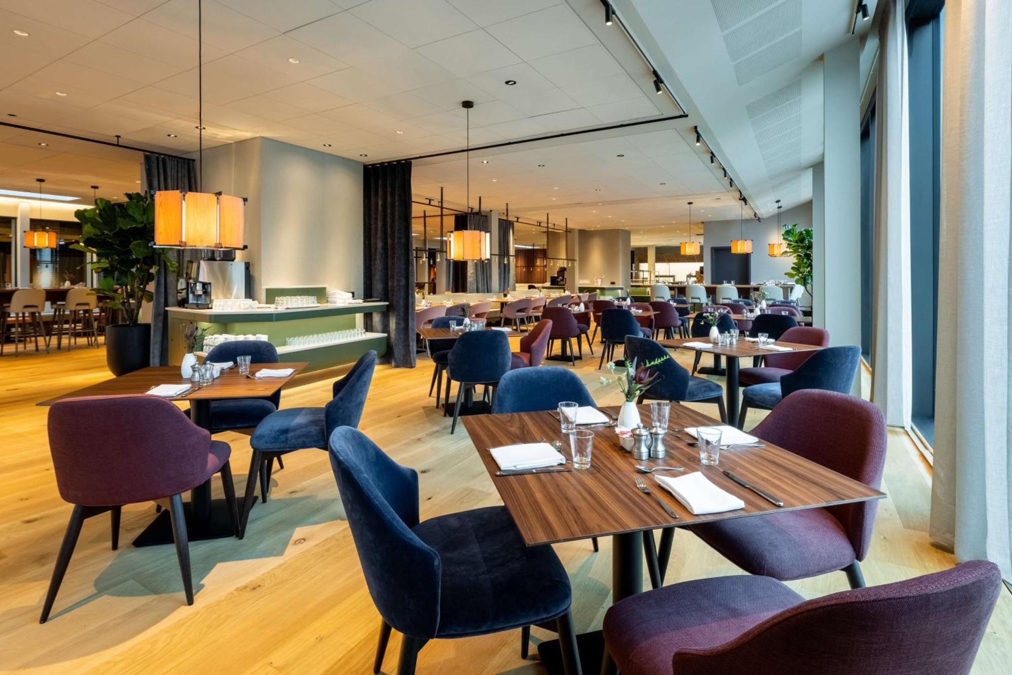 Nh Collection Copenhagen Hotel Ngoại thất bức ảnh The photo showcases a modern restaurant interior with a spacious and elegant design. It features wooden flooring and a combination of light and dark furnishings. There are several tables set for dining, each with utensils and glasses. The chairs come